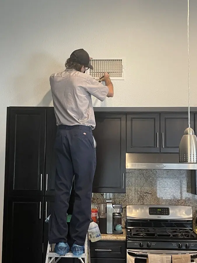 Technician inspecting an air vent during HVAC service in Oregon